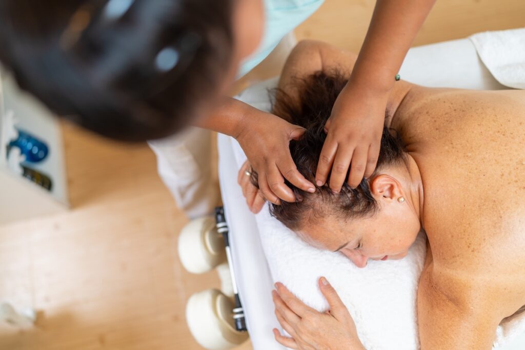 Bird's eye view of a woman getting a cranial massage in a clinical setting.