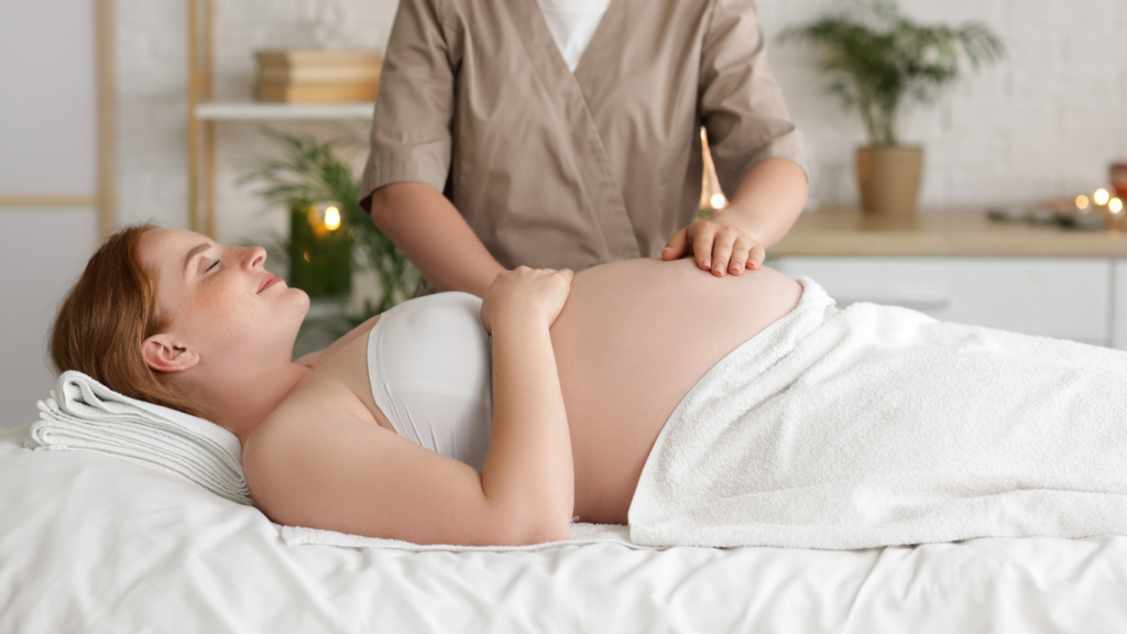 A pregnant woman lies on her back. She is being massaged.
